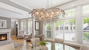 A spacious living room with a fireplace, a chandelier, and a dining area with a glass table. - Villa Bella (Minneapolis)