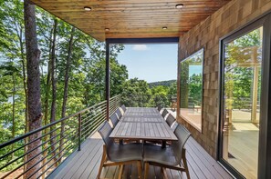 Una terraza al aire libre con una mesa y sillas, rodeada de árboles y vistas al paisaje.
