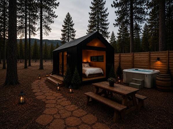 Una cabaña con cama, jacuzzi y terraza de madera.