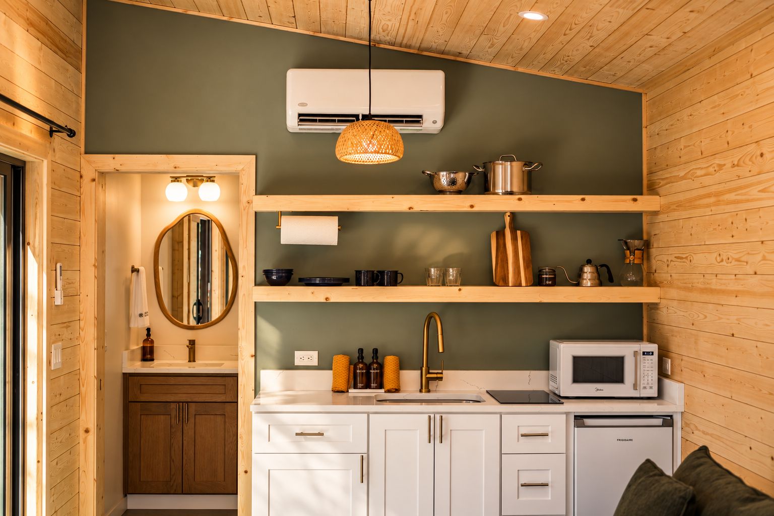 A compact kitchen with wooden cabinetry, a built-in microwave, and a hanging light fixture.
