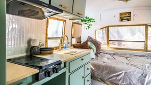 A compact kitchen with a gas stove, a sink, and a window with a view. - Ponderosa Pines Resort (Parks)
