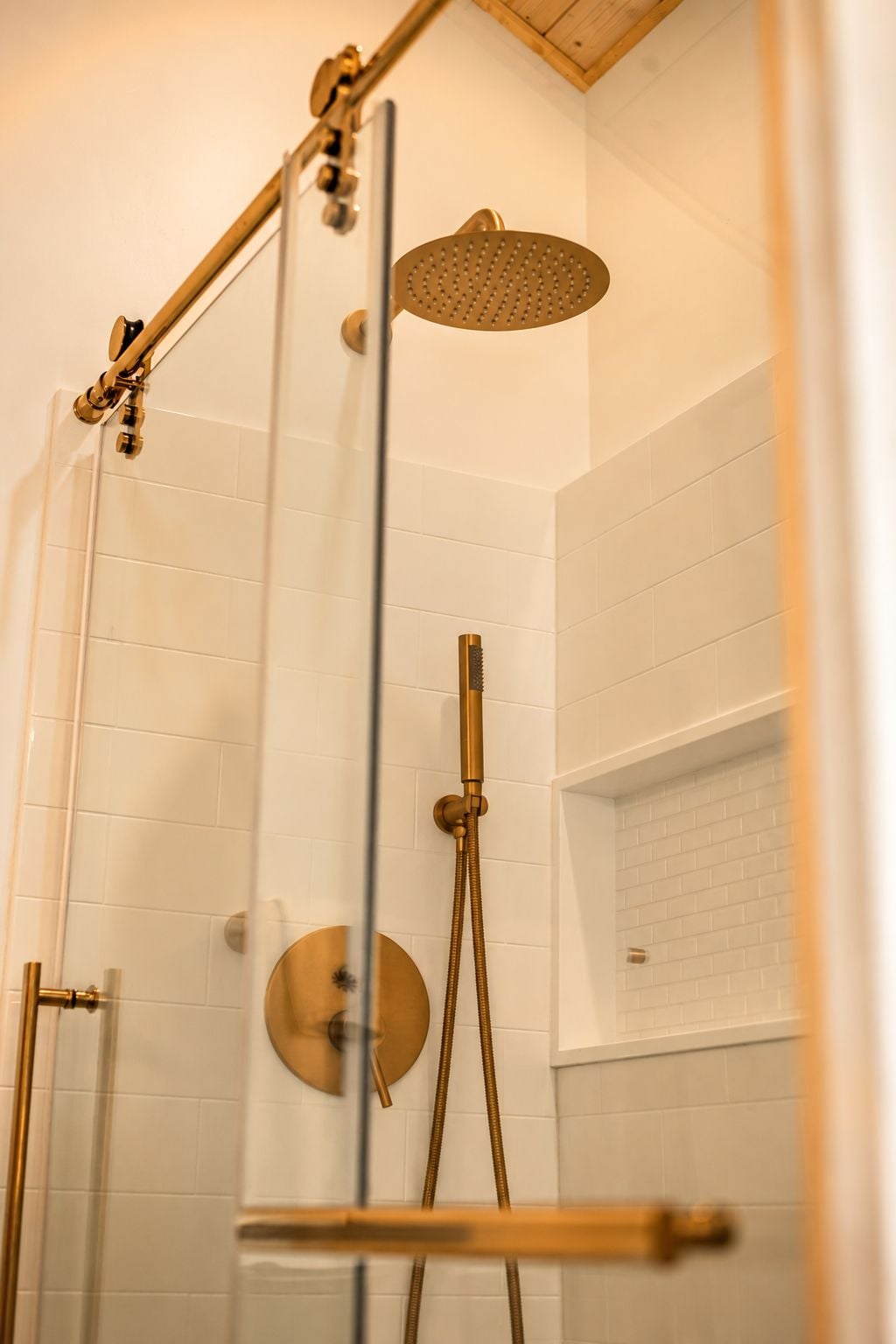 Eine Dusche mit Glastür, Handbrause und fest installierter Duschkopf.