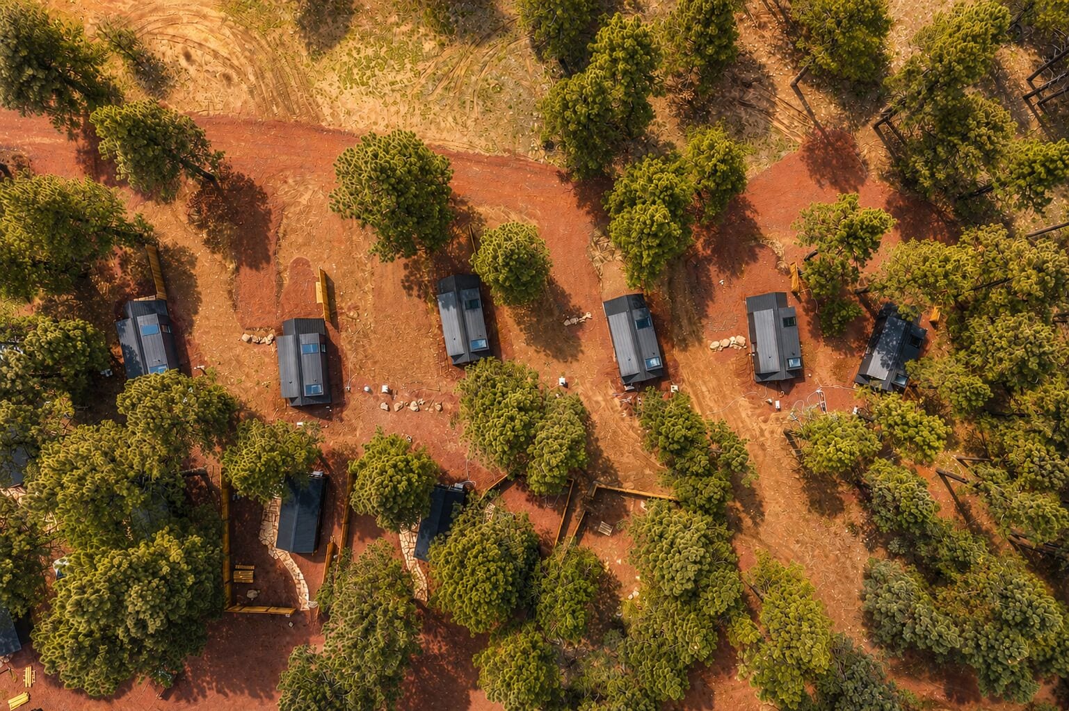 An aerial view of a property with several small buildings and dense greenery.