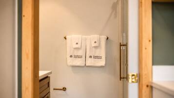 Un baño con inodoro, lavamanos y dos toallas colgadas en un perchero.