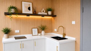 A modern kitchen with white cabinetry, gold handles, a black sink, and a wooden backsplash. - Ponderosa Pines Resort (Parks)