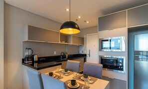 A modern kitchen with built-in appliances, a dining area with a table set for two, and a large pendant light. - House w/ Garage in Rio Vermelho Tstedf0401 (Salvador)