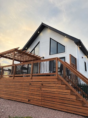 Ein modernes Haus mit einer Holzterrasse, groĂen Fenstern und einem geneigten Dach.