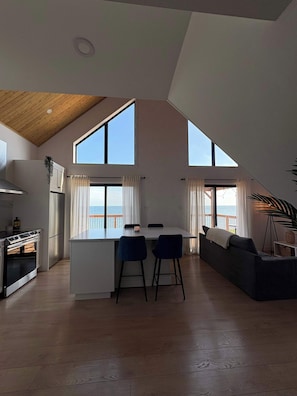 Una cocina moderna con una isla central, un comedor con dos sillas y un sofá.