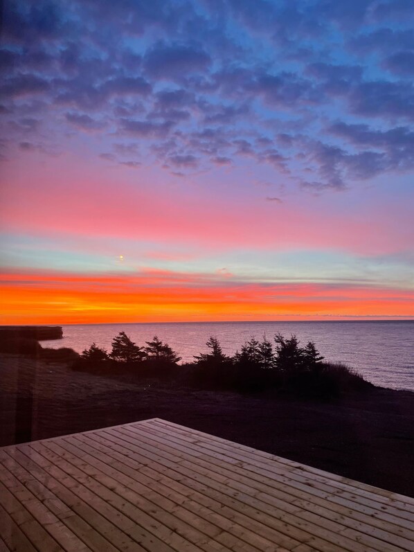 A wooden deck overlooking a beach with a sunset sky.