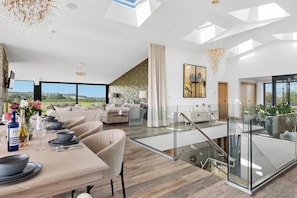 A modern interior with a dining area, a staircase, and a view of the outdoors. - The Retreat (Ivybridge)