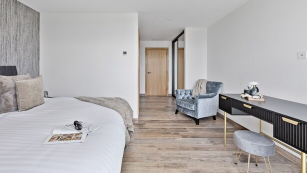 Une chambre à coucher moderne avec un grand lit, un bureau et une chaise.