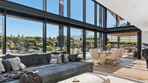 Un intérieur moderne avec un grand canapé, un coin repas et une vue sur un jardin aménagé.