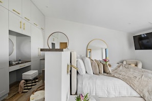 Ein Schlafzimmer mit einem Bett, einem Schreibtisch, einem Stuhl, einem Fernseher und einem Kleiderschrank.