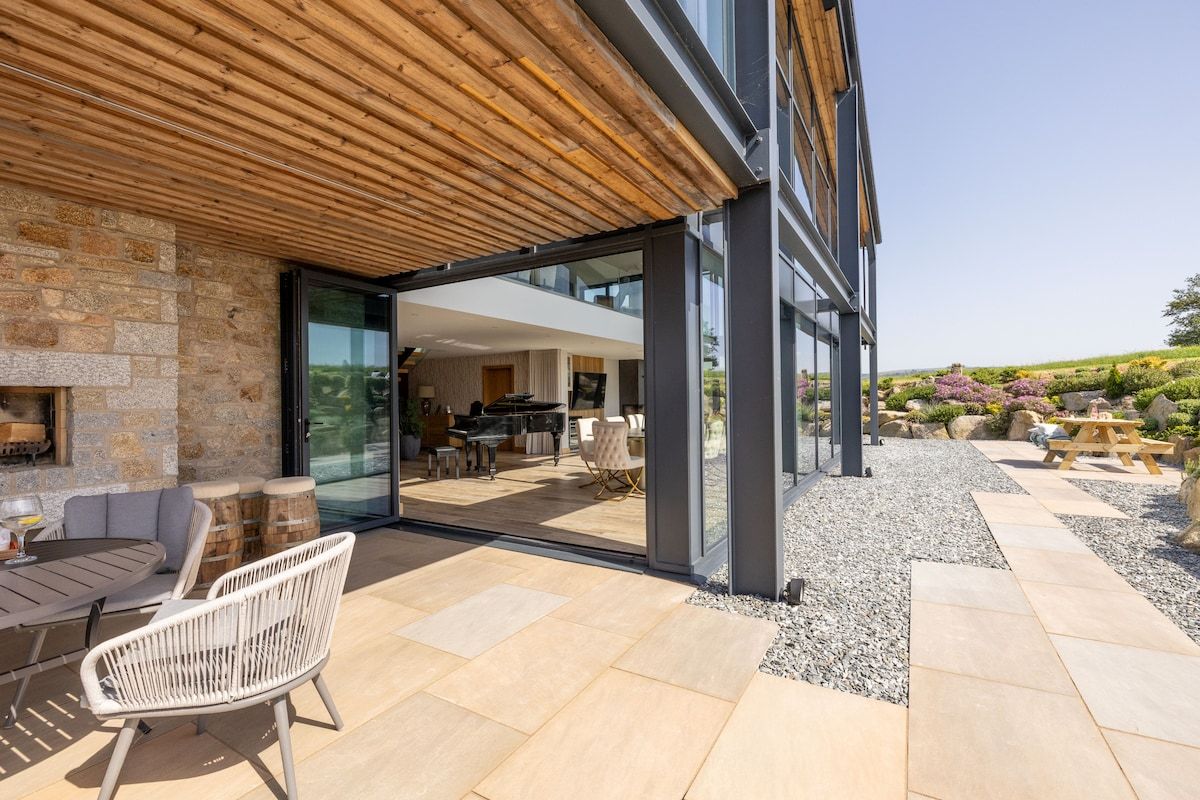 Un patio al aire libre con suelo de piedra, sillas de mimbre blanco y una mesa.