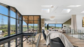 Ein modernes Interieur mit einem Glasbalkon, einem Essbereich und Blick auf die Landschaft.