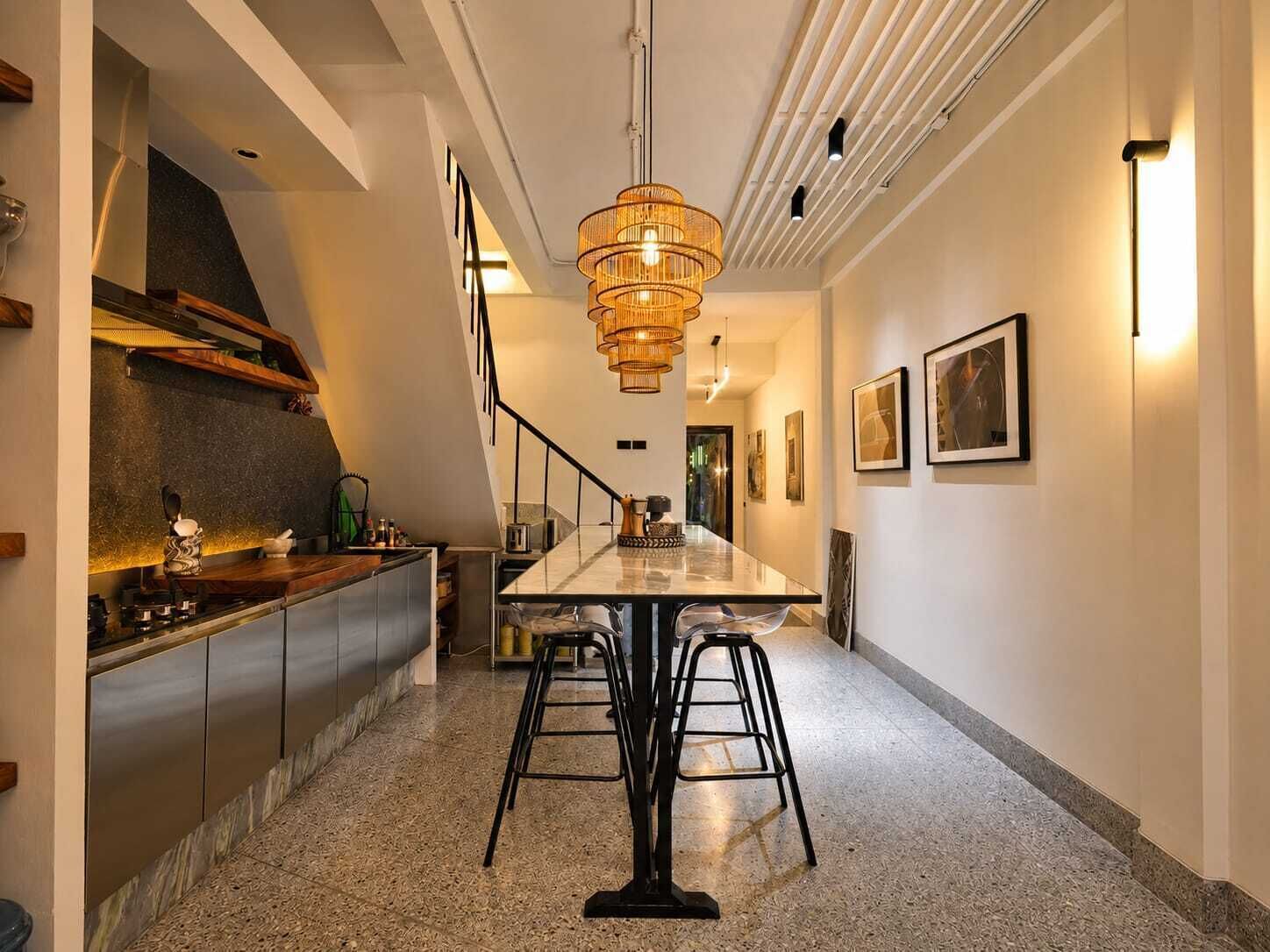 A modern kitchen with a central island, a staircase, and a dining area with bar stools.