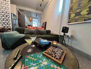 A living room with a green sofa, a chessboard, a Monopoly board, and a candle on a round table. - 10 min BTS 1Gbs WIFI NFLIX Full Kitchen HomeCinema (Khet Phra Khanong)