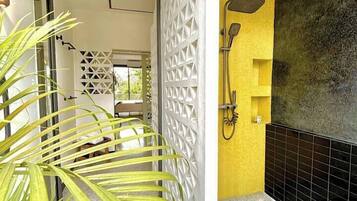 A modern bathroom with a shower, a yellow accent wall, and a white decorative partition.