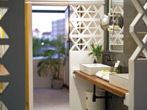 Een badkamer met een modern design, met een houten wastafelmeubel, een spiegel en een potplant.