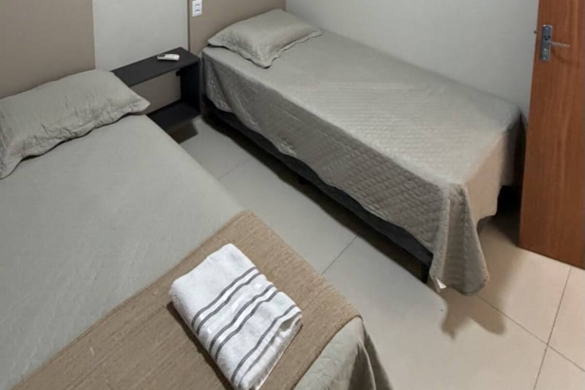 A small, clean room with two single beds, a nightstand, and a door.