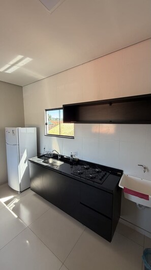 Una cocina moderna con estufa a gas integrada, refrigerador y ventana con vista a un jardín.