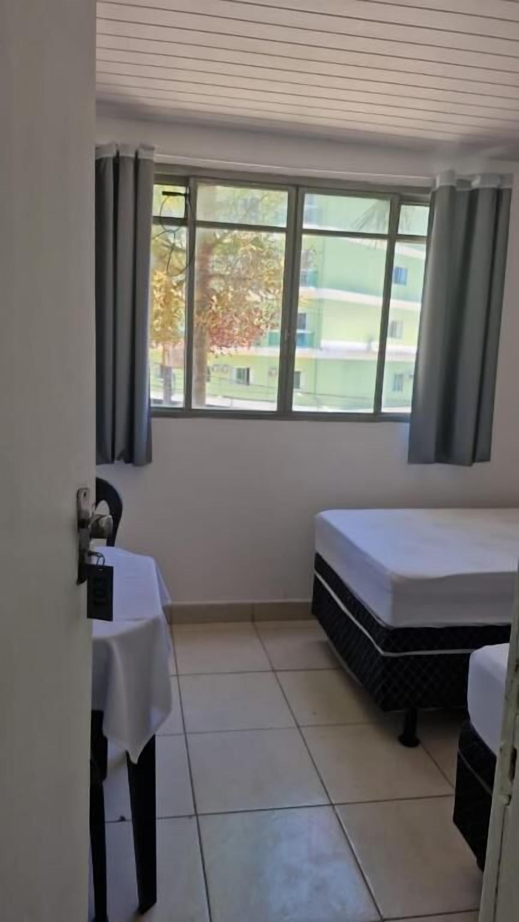 A small room with a bed, a table, and a window.