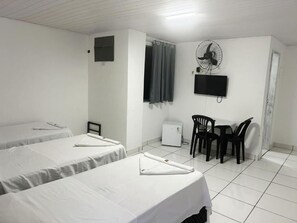 A hotel room with two beds, a desk, a chair, a TV, and a fan. - Hotel Balneário (Angra dos Reis)
