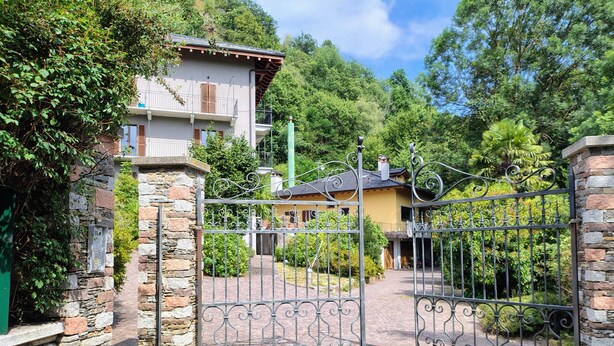 A gated entrance with stone walls, a paved path, and a building with a balcony. - In the shade of a beech tree: An oasis of tranquility just a few minutes from the lake (Miasino)