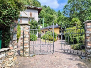 Ein verschlossenes Tor mit Steinmauern, einem gepflasterten Weg und einem Gebäude mit einem Balkon.