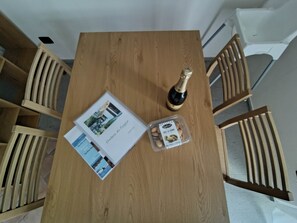 Ein Holztisch mit einer Champagnerflasche, einer Broschüre und einer Mandelschachtel.