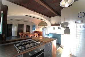 Eine Küche mit Gasherd, Holz Arbeitsplatte und einem Essbereich mit Stühlen und Tisch.