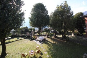 Ein Garten mit einer Steinsitzbank, einem Tisch und Stühlen.