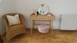 A room with a wicker chair, a wooden vanity with a mirror, a pink stool, and a radiator. - Orta Blu Lake House: Spectacular view of Lake Orta, great (Miasino)