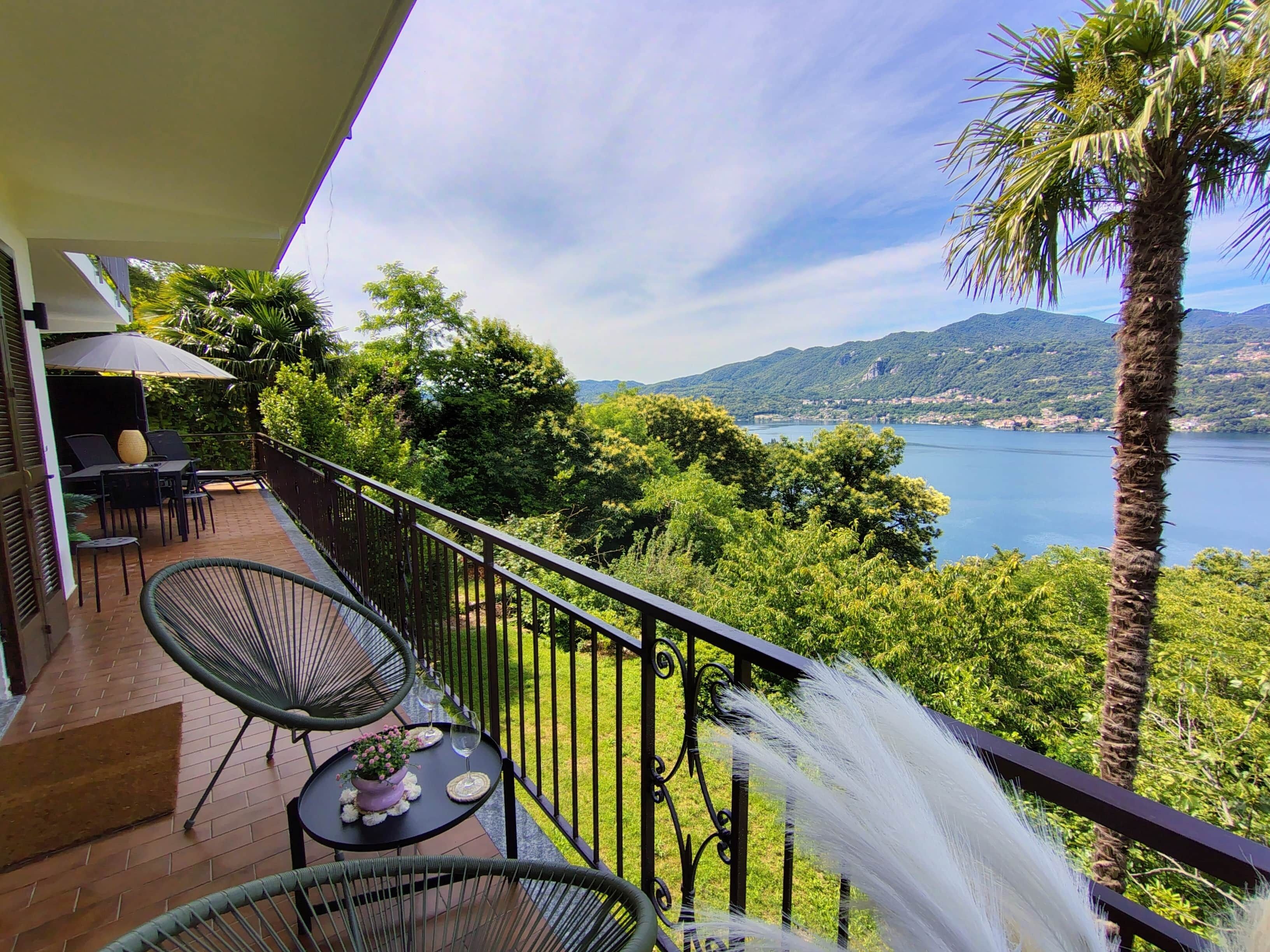 Ein Balkon mit Gartenmöbeln, Blick auf einen See und umgebende Grünflächen.