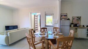 A dining area with a round table, wooden chairs, and a TV in the background. - Orta Blu Lake House: Spectacular view of Lake Orta, great (Miasino)