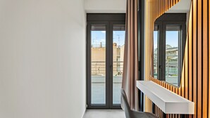A modern apartment with a sliding glass door leading to a balcony, a built-in bench, and a wooden panel wall. - Athens Vein (Athens)