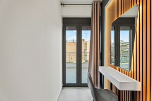 Un appartement moderne doté d’une porte-fenêtre coulissante donnant sur un balcon, d’un banc intégré et d’un mur revêtu de panneaux en bois.