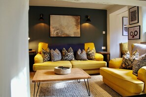 Ein Wohnzimmer mit gelber Sofagarnitur, einem hölzernen Couchtisch und einem großen abstrakten Gemälde an der Wand.