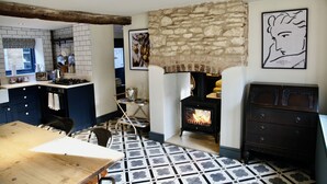 A kitchen with a stone wall, a wood-burning stove, and a tiled floor. - Cosy Cotswold Cottage with Fireplace and Courtyard (Oxfordshire)