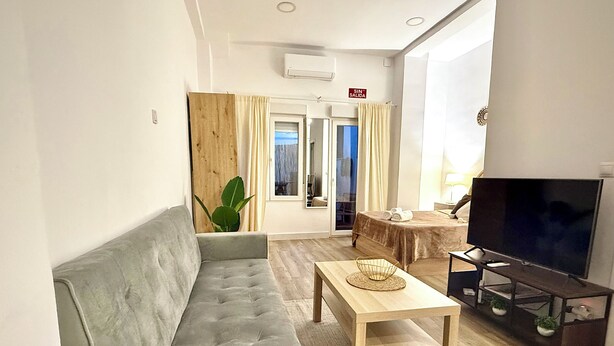 Una sala de estar moderna con un sofá, una mesa de centro, un televisor y un balcón con vistas.