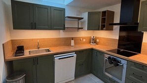 A modern kitchen with a skylight, built-in dishwasher, oven, and stainless steel sink.