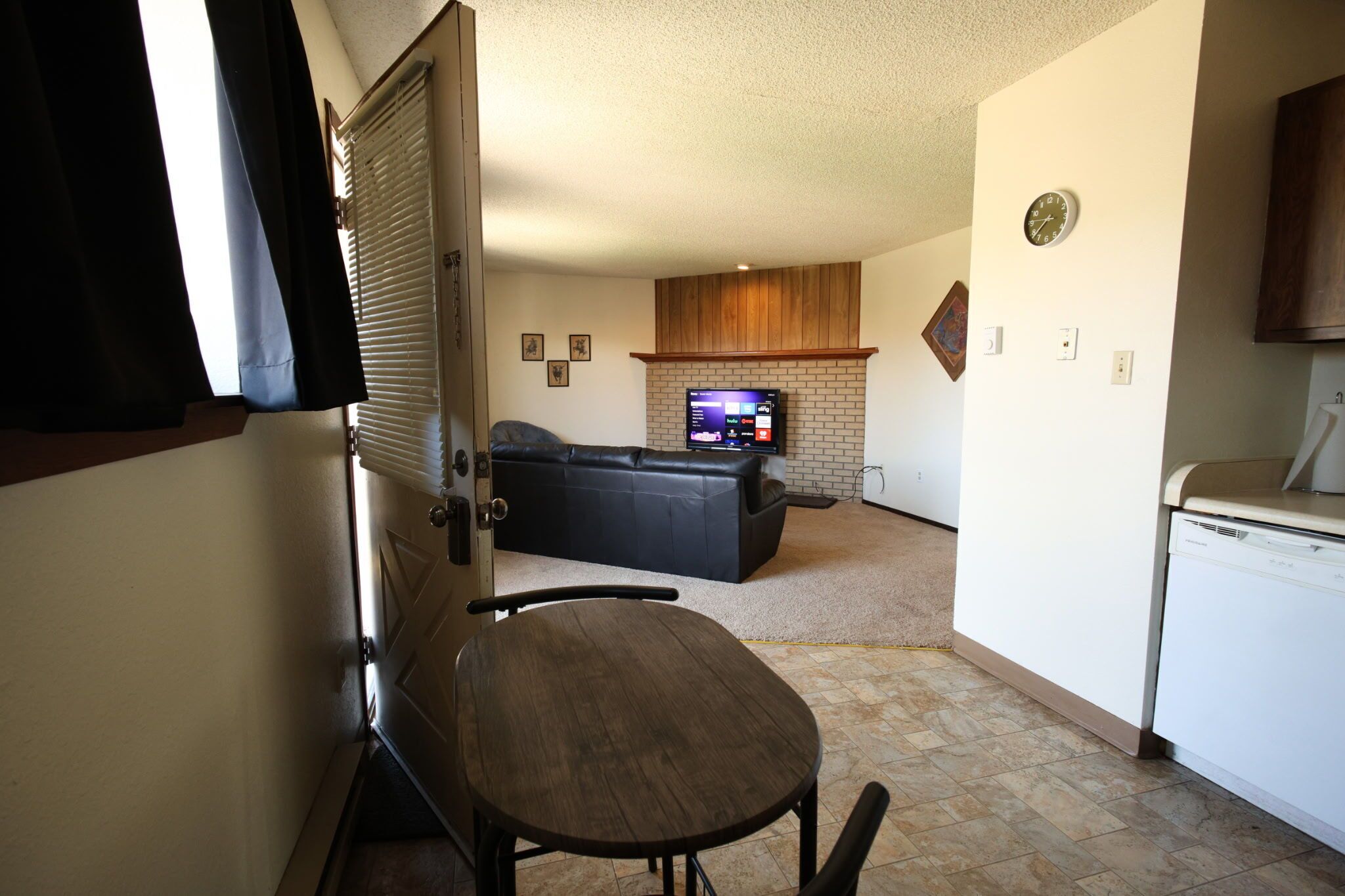 Una habitación con chimenea, televisión, sofá y mesa de comedor.