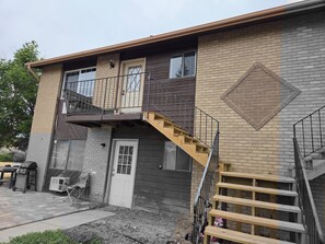 A two-story building with a balcony, a wooden staircase, and a garage.