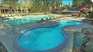 Una piscina de borde curvo, sillas de descanso y un borde de piedra.
