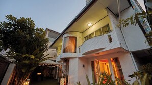 Un immeuble à plusieurs étages doté d’une façade incurvée, d’un éclairage extérieur et d’un balcon.