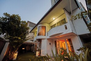 A multi-story building with a curved facade, outdoor lighting, and a balcony. - Sleep10 | 100" Cinema | Quiet Gated Retreat | Mall (Khet Khlong Toei)