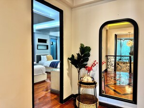 A hotel room with a bed, bedside table, and a mirror reflecting the room. - Sleep10 | 100" Cinema | Quiet Gated Retreat | Mall (Khet Khlong Toei)