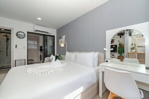 Een moderne hotelkamer met een groot bed, een bureau, een spiegel en een douche.