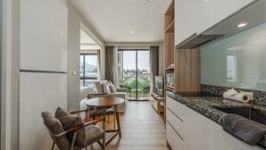 A modern kitchen with a dining area, large windows, and a view of the outside. - Comfy 1BR Getaway by Beach & Shops- diamond C176 (Tambon Choeng Thale)