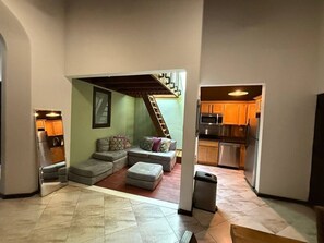 A compact living space with a sofa set, a staircase, and a kitchen area. - Elegant San Juan Loft for 8 • The Mezzanine (San Juan de Puerto Rico)